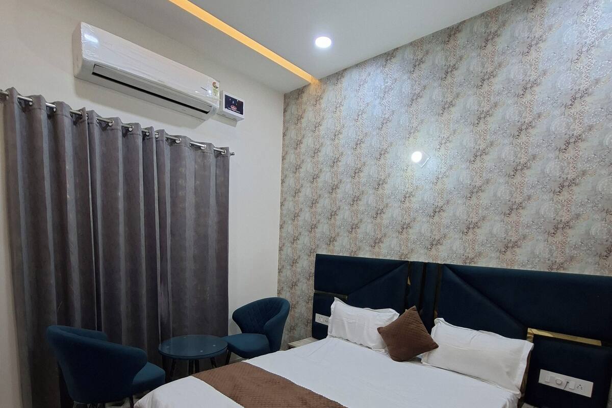Ein Hotelzimmer mit Bett, Nachttisch, Stuhl und Klimaanlage.
