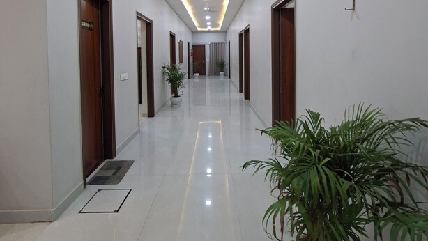 A long, well-lit hallway with a ceiling fan, recessed lighting, and a decorative wall clock. - Wishotel Xpress Hotel Crown Classic Villa (Ludhiana)