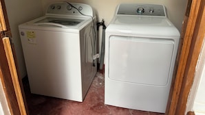 A laundry room with two white washing machines and a white dryer.