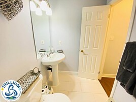 A bathroom with a white sink, toilet, and mirror. A towel rack is visible on the wall.