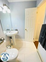 Un baño con lavamanos pedestal, inodoro, espejo y puerta.