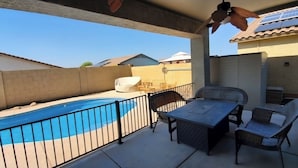 A covered patio with a swimming pool, outdoor furniture, and a view of neighboring houses. - Spacious 4-bedroom house in welcoming Goodyear with Dual AC and Pool (Goodyear)