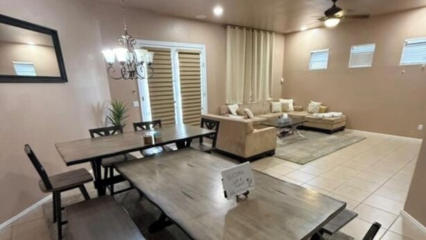 A spacious living room with a large dining table, a sofa set, and a ceiling fan. - Spacious 4-bedroom house in welcoming Goodyear with Dual AC and Pool (Goodyear)