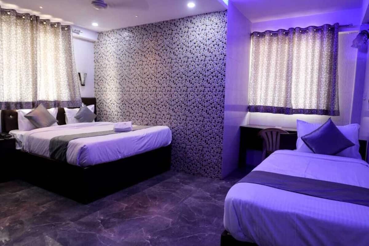 A hotel room with two beds, a stone-patterned wall, and curtains.