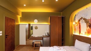 Ein Hotelzimmer mit Bett, Schreibtisch, Spiegel und einem an der Wand hängenden Kunstwerk.