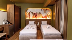 Ein Hotelzimmer mit zwei Betten, einem Schreibtisch, einer Kaffeemaschine und einem Wandbild.