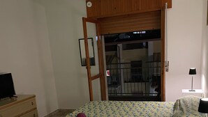 A bedroom with a bed, a dresser, a nightstand, a door leading to a balcony, and patterned floor tiles. - Cozy Double Room with Sea and Mountain view Terrace (Diamante)