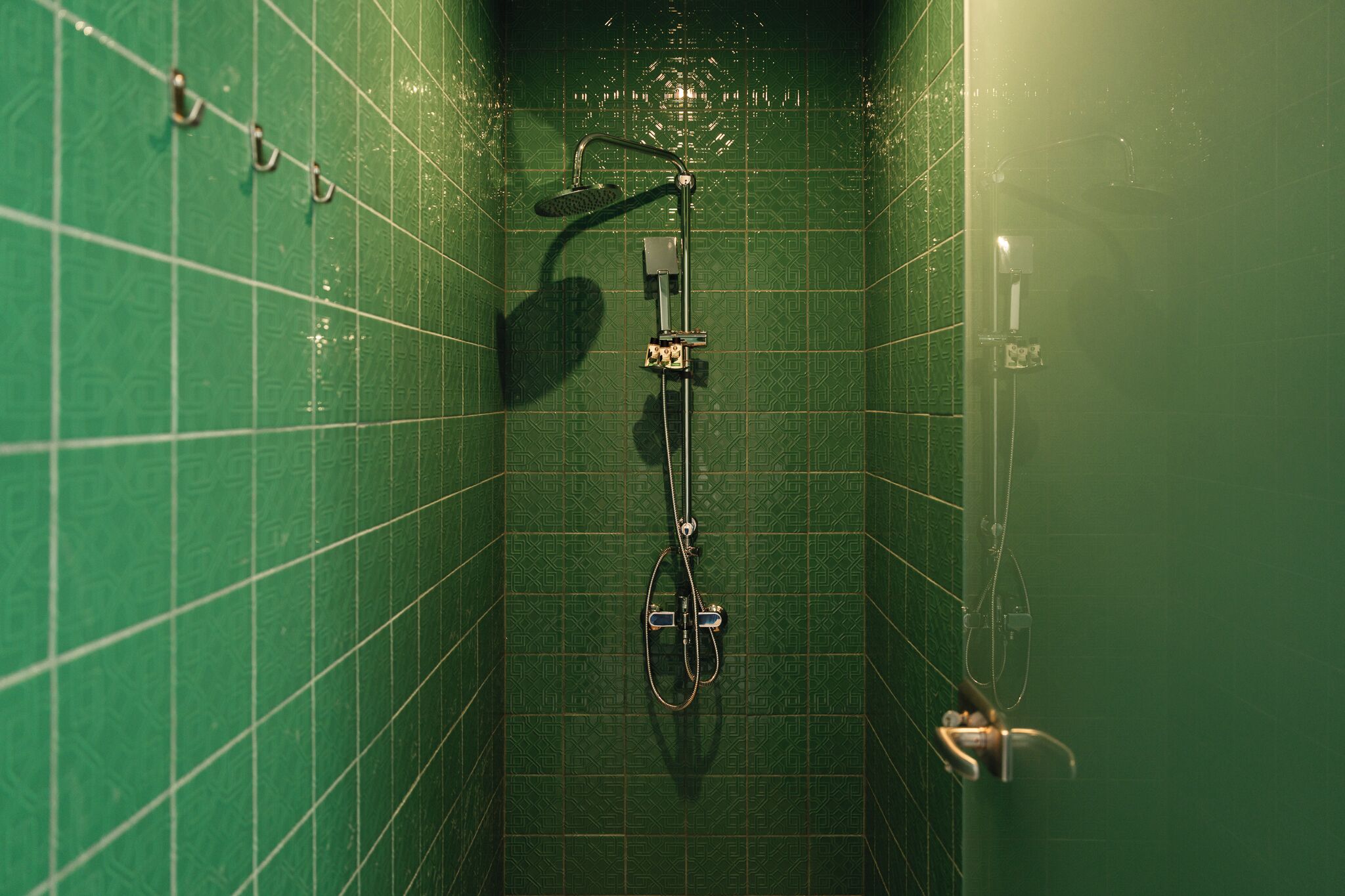 A small, enclosed shower area with a handheld showerhead and a wall-mounted faucet.