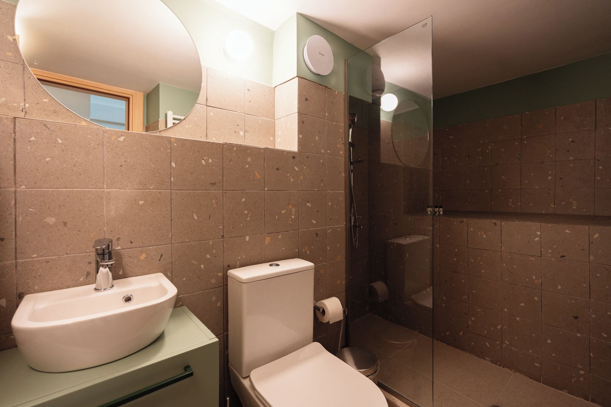 A modern bathroom with a freestanding sink, toilet, and glass-enclosed shower.