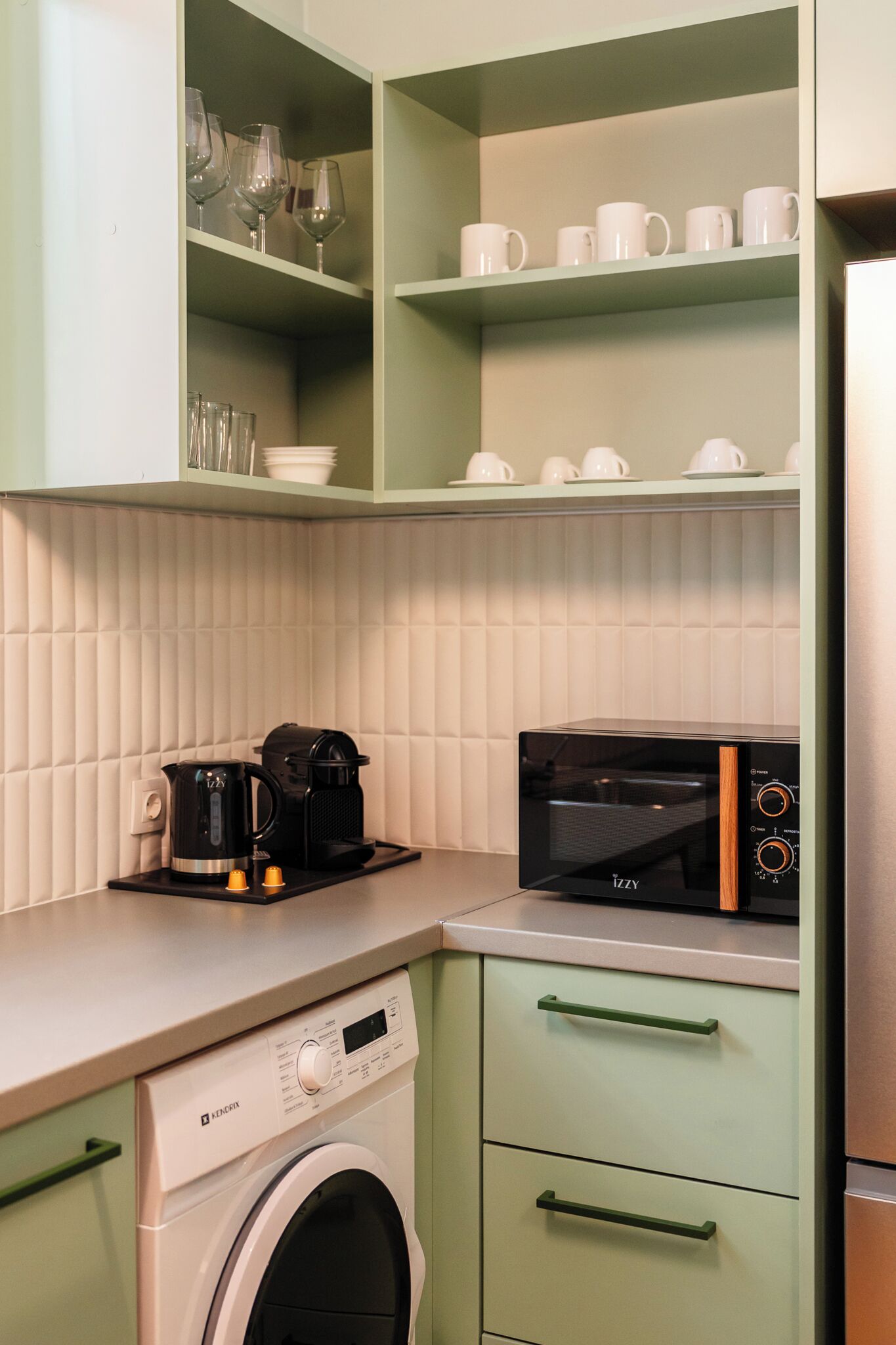 A compact kitchen with a washing machine, a coffee maker, and a microwave.