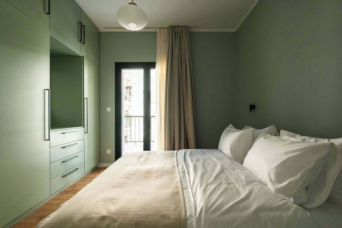 A bedroom with a bed, a wardrobe, and a door leading to an outdoor area.