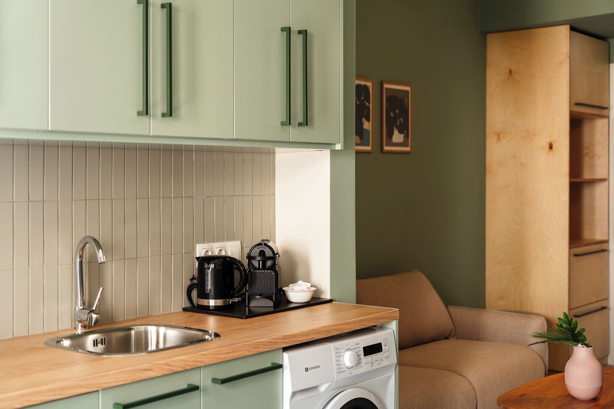 A compact kitchen with a sink, a coffee maker, and a washing machine.
