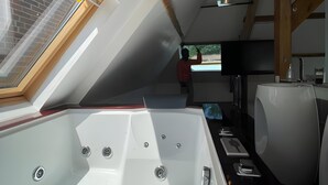 A modern bathroom with a large bathtub, skylight, and wooden beams. - Estate in Saint-pavace Near Le Mans Circuit (Saint-Pavace)