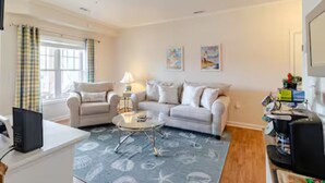 A living room with a sofa, armchair, coffee table, and a television.
