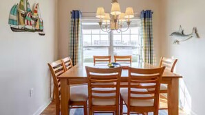 A dining area with a wooden table and chairs, a chandelier, and decorative wall art.