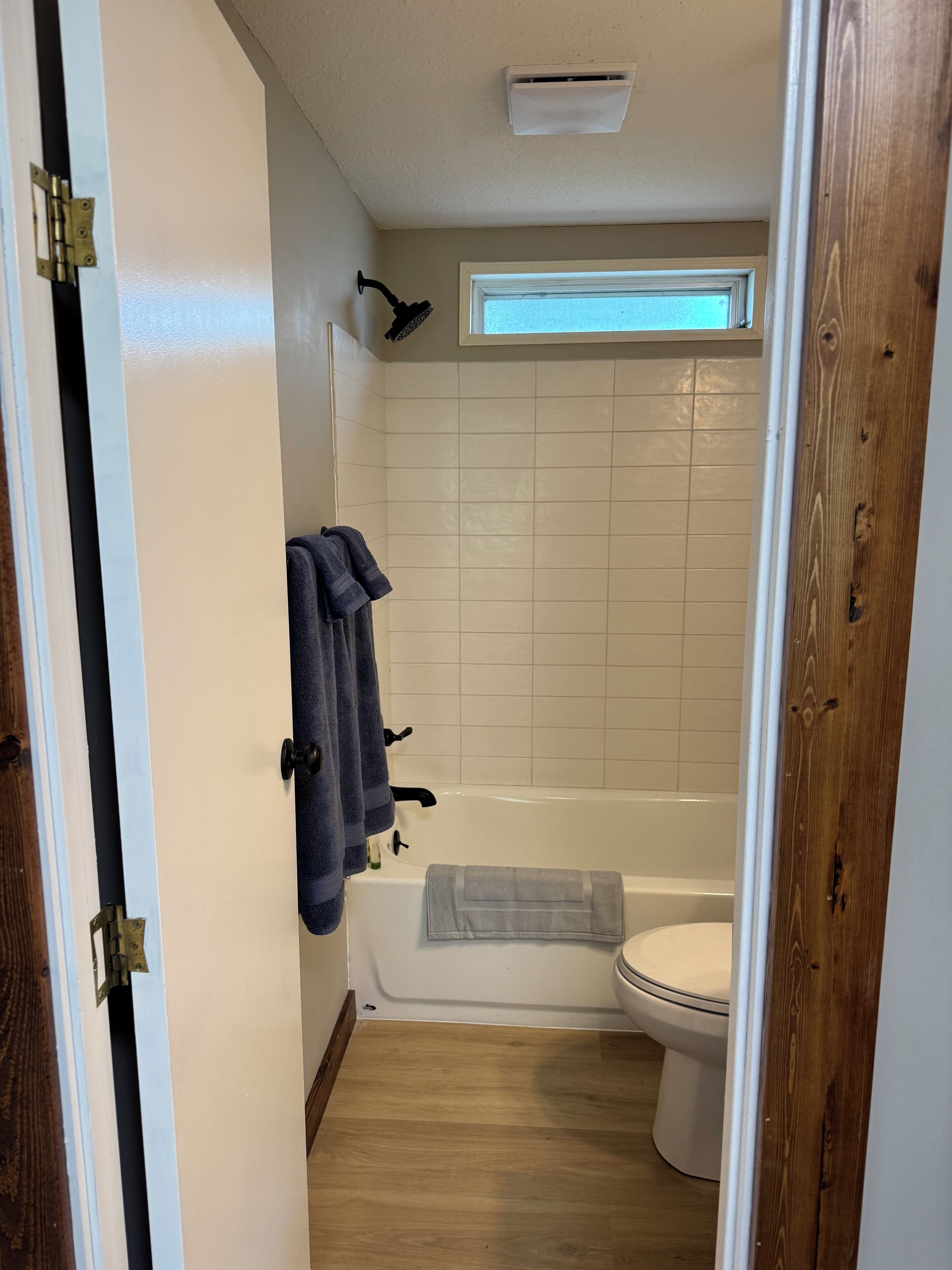 Une salle de bain avec une baignoire, des toilettes et une fenêtre au-dessus du lavabo.