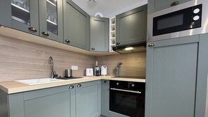 A modern kitchen with grey cabinets, a built-in oven, a microwave, and a sink. - Duplex in Le Mans Near 24 Hours Circuit (Le Mans)