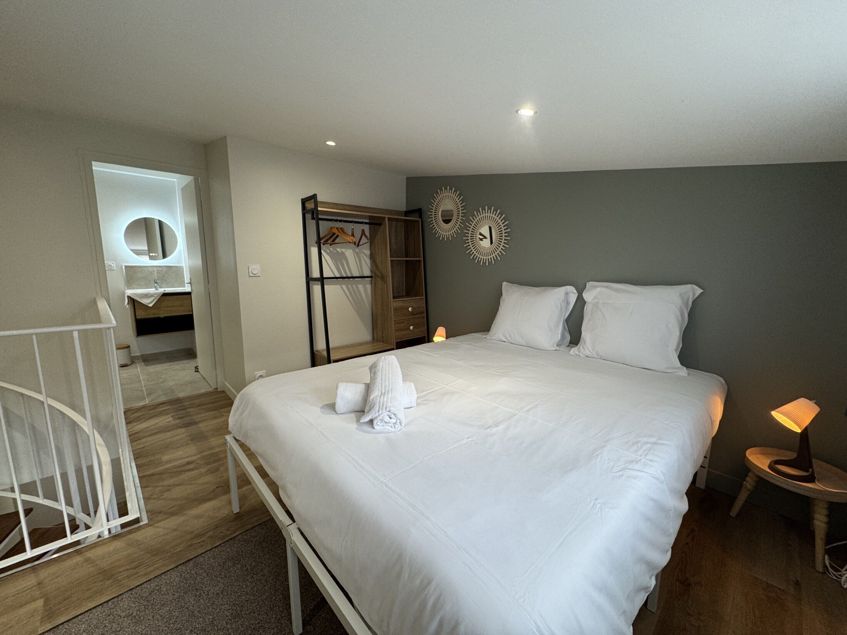 A bedroom with a large bed, bedside lamps, a wardrobe, and a mirror.
