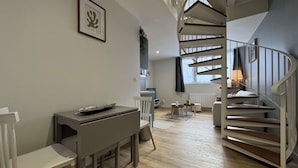 A modern living space with a dining area, a staircase, and a view of the city. - Duplex in Le Mans Near 24 Hours Circuit (Le Mans)