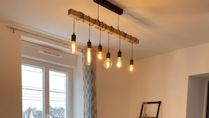 Una sala de estar con un sofá color turquesa, una mesa de centro de vidrio y una estantería de madera con libros y objetos decorativos.