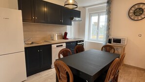Una cocina compacta con electrodomésticos modernos, una mesa de comedor de madera y sillas.
