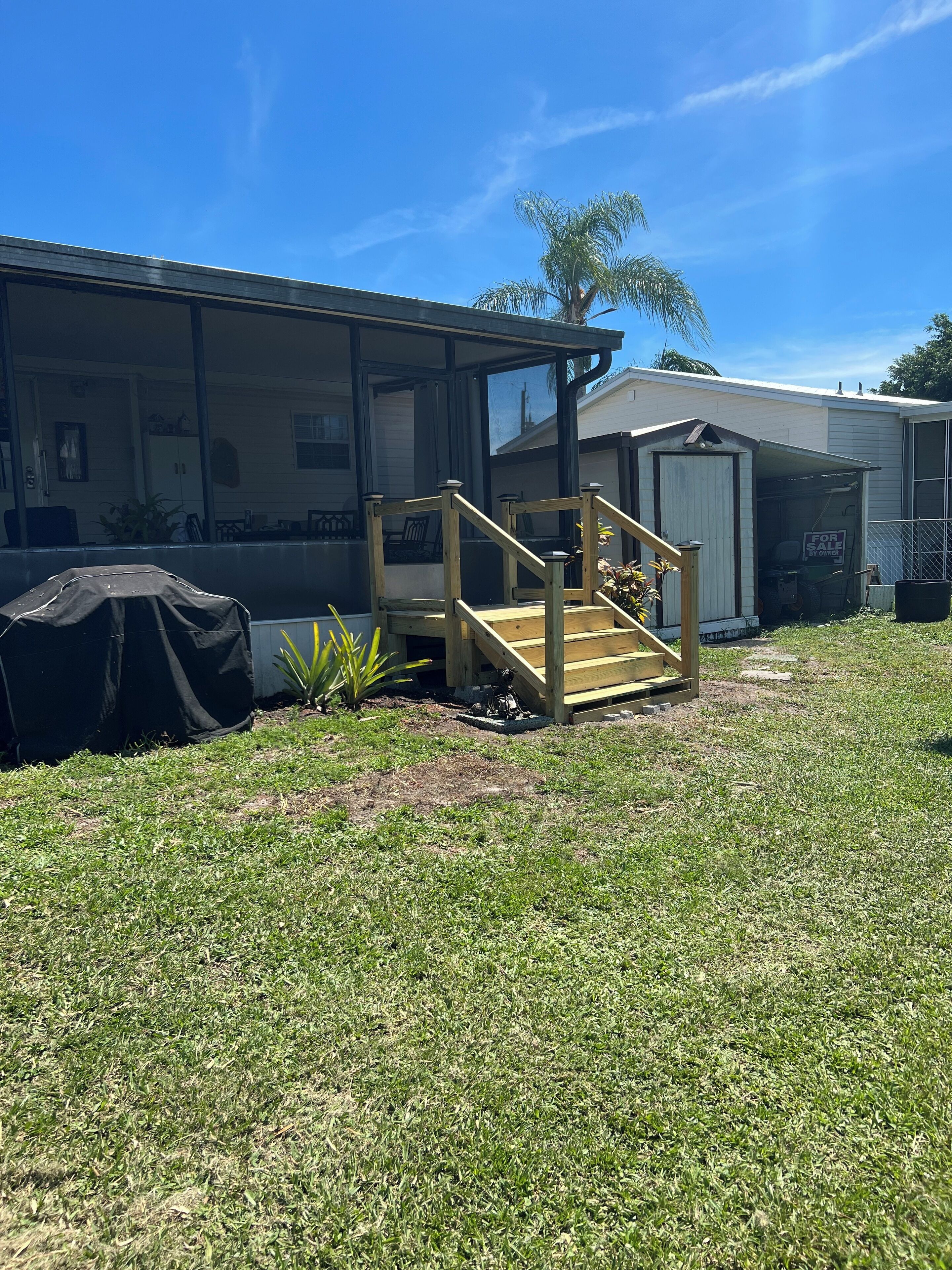 A residential property with a covered porch, a garage, and a small shed.
