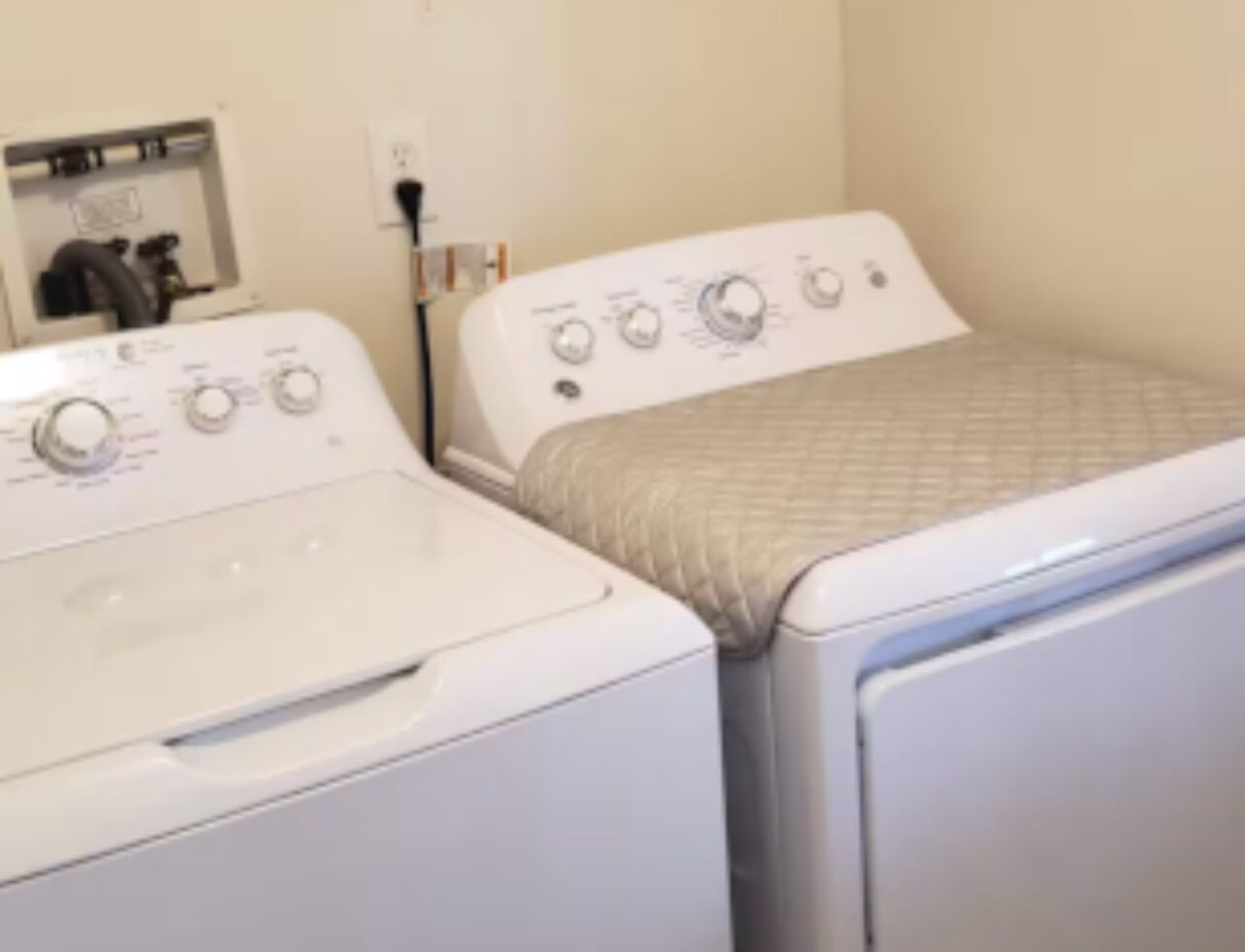 A laundry room with two white front-loading washing machines and a dryer.