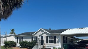 A single-story house with a front porch, a garage, and a covered driveway. - “Our Lakeside Oasis” is a Cozy 2-bedroom house in charming Okeechobee. (Okeechobee)