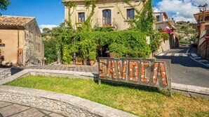 A sign with 'SAVELA' written on it, a building with a tiled roof, and a street with a pedestrian crossing. - 'Executive Suite' room with private balcony, sea view, Wi-Fi and air conditioning (Savoca)