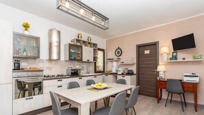 A modern kitchen with a dining area, built-in appliances, and a flat-screen TV. - 'Executive Suite' room with private balcony, sea view, Wi-Fi and air conditioning (Savoca)