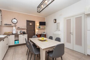 Uma cozinha moderna com uma mesa de jantar, cadeiras, um relógio e uma televisão.