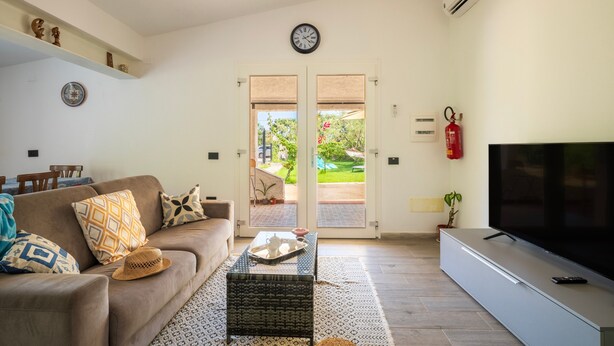 A living room with a sofa, coffee table, TV, and a door leading to a patio. - Holiday Home 'Dammar' with Mountain View, Wi-Fi and Air Conditioning (Tertenìa)