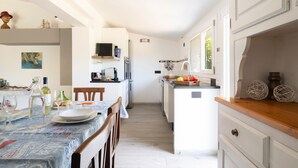 A modern kitchen with white cabinetry, a dining area with a table set for two, and a small island with a sink. - Holiday Home 'Dammar' with Mountain View, Wi-Fi and Air Conditioning (Tertenìa)