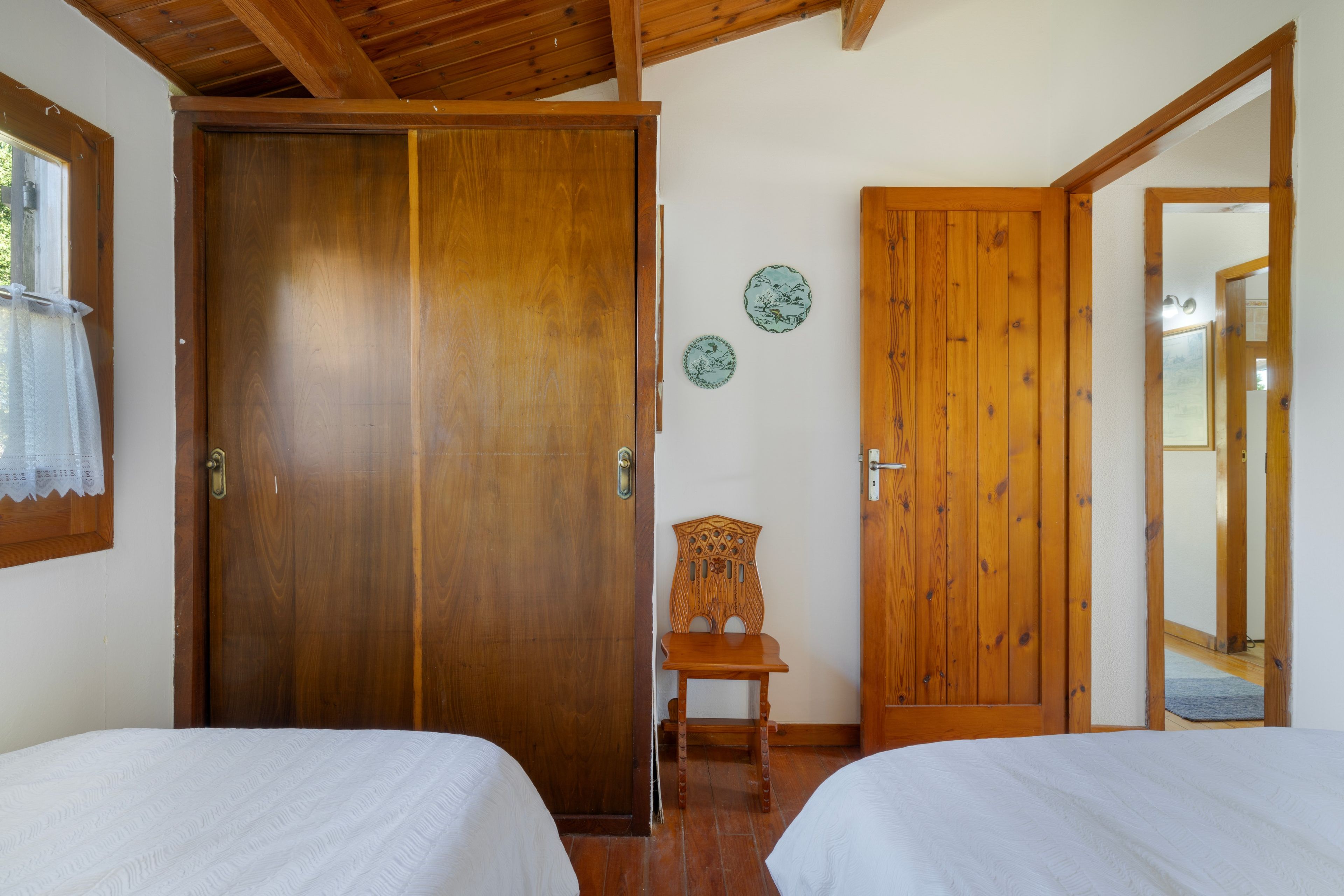 Een kamer met twee houten bedden, een houten stoel en een deur met een spiegel.