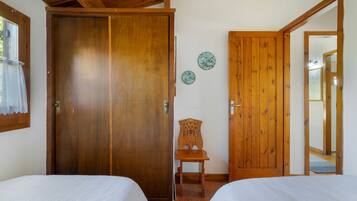 Een kamer met twee houten bedden, een houten stoel en een deur met een spiegel.