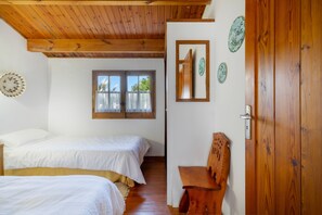 Une chambre avec deux lits, une porte en bois et une fenêtre avec des rideaux.