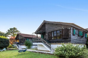 A traditional wooden house with a porch and a staircase leading to the entrance.