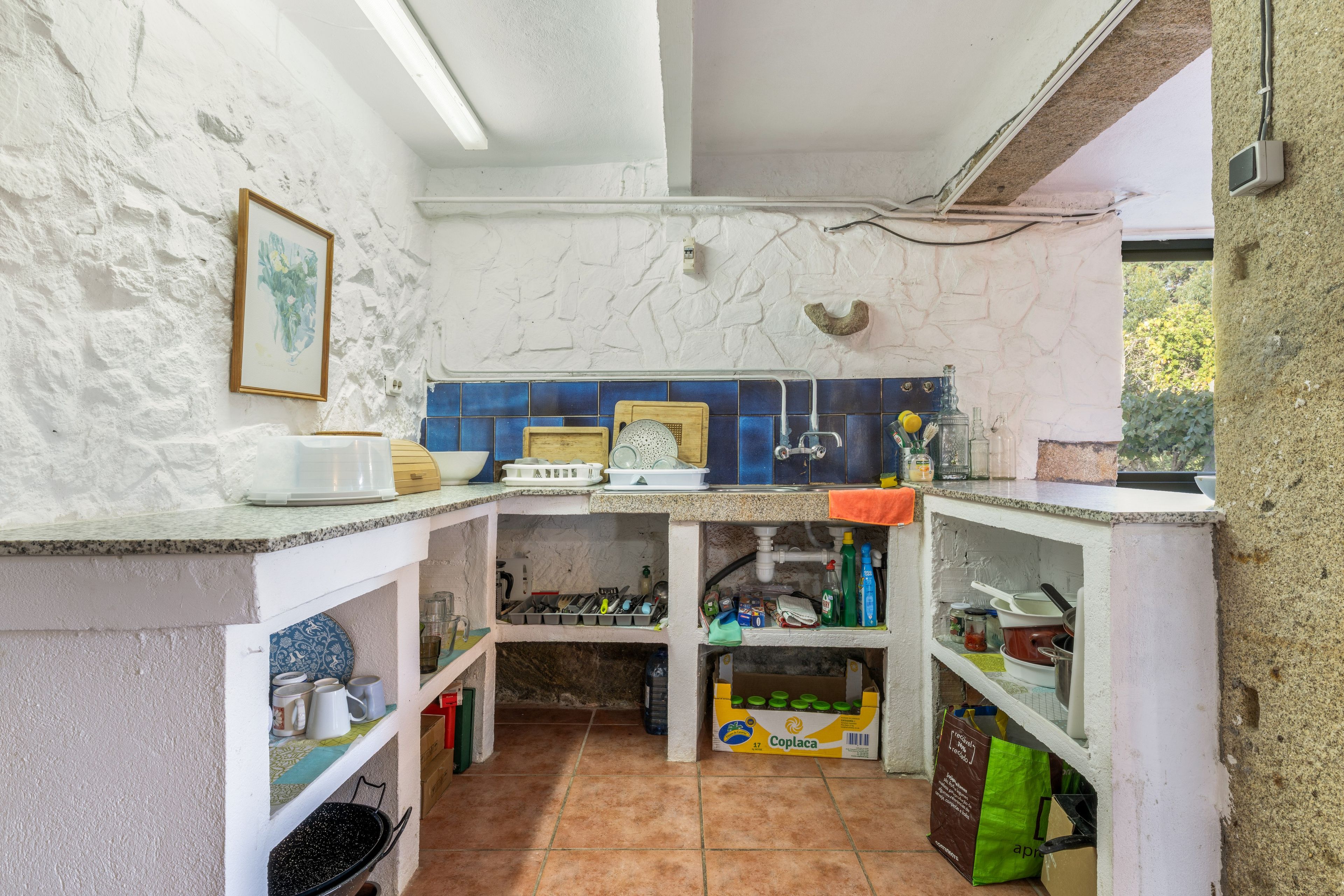 A compact kitchen with white walls, blue tiles, and a tiled floor.