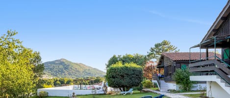 A well-maintained garden with a fountain, outdoor seating, and a view of a mountain.