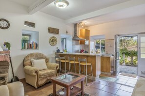 A cozy living room with a sofa, a coffee table, and a bookshelf. - Holiday Home 'Cottage' with Mountain View, Shared Pool and Wi-Fi (As Eiras)
