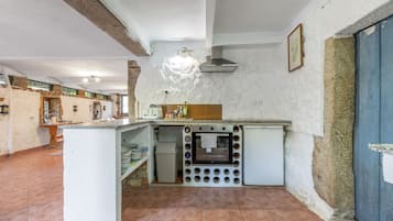 Cuina compacta amb forn integrat, petita pica i taulell equipat amb diversos objectes de cuina.