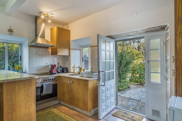 A kitchen with wooden cabinets, a stainless steel range, and a window overlooking a garden.
