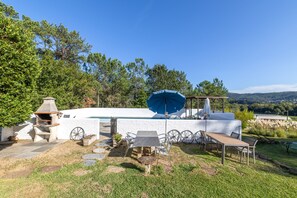 A patio area with a barbecue grill, outdoor seating, and a view of a pool and hills. - Holiday Home 'Cottage' with Mountain View, Shared Pool and Wi-Fi (As Eiras)