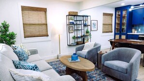 A living room with a sofa, armchairs, a coffee table, a bookshelf, and a dining area with a table and chairs. - Uptown Peach ~ Great base 4 your Waco adventures! (Waco)