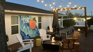 An outdoor deck with string lights, a mural, and outdoor seating. - Uptown Peach ~ Great base 4 your Waco adventures! (Waco)