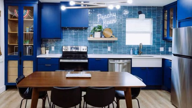A modern kitchen with blue cabinets, a wooden dining table, and a stainless steel refrigerator. - Uptown Peach ~ Great base 4 your Waco adventures! (Waco)