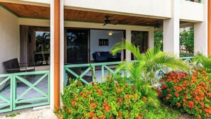 A covered outdoor seating area with a view of the interior. - Elegant Condo with Brand-New Fixtures, Shaded Tropical Terrace, and Secluded Beach Access (Playa Flamingo)