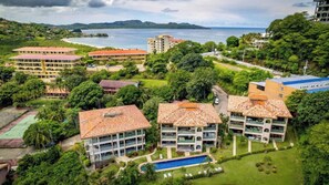 A resort with multiple buildings, a swimming pool, and a view of the sea.