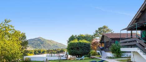 A well-maintained garden with a fountain, outdoor seating, and a view of a mountain.