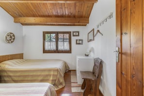 A bedroom with two beds, a desk, and a chair.